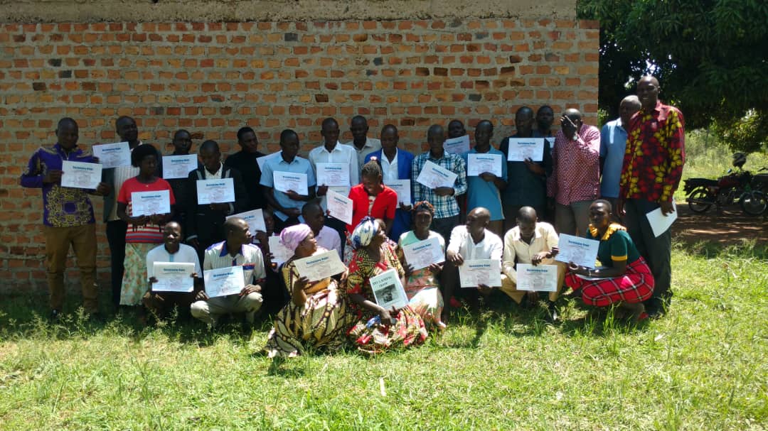 Reclaiming Hope graduates holding certificates in a village